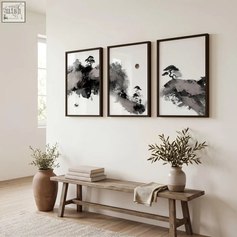 Three framed black and white ink wash calming wall art prints with maroon sun and black pine trees hang on a white wall