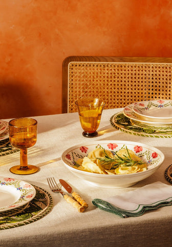 White ceramic camilla pasta bowl with red and green floral pattern filled with pasta and fresh rosemary garnish