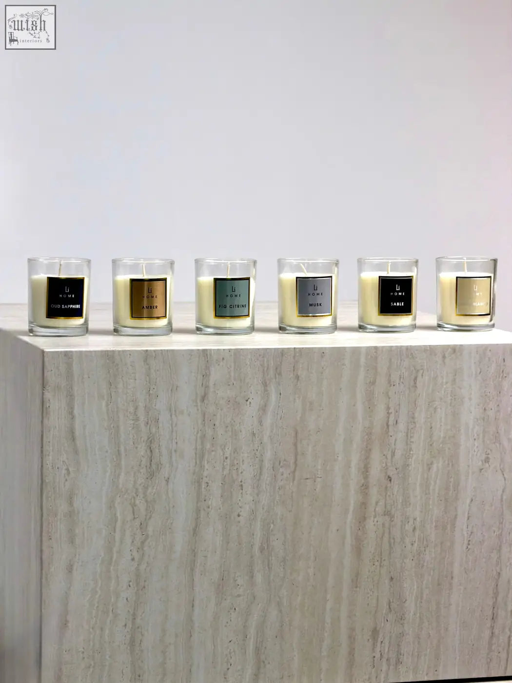 Six elegant glass candle jars with creamy white wax and metallic accents in a minimalist candle discovery set