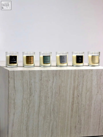 Six elegant glass candle jars with creamy white wax and metallic accents in a minimalist candle discovery set
