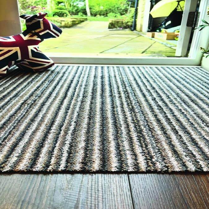 A candy washable mat with a striped design in gray and beige featuring a plush textured looped pile washable mat