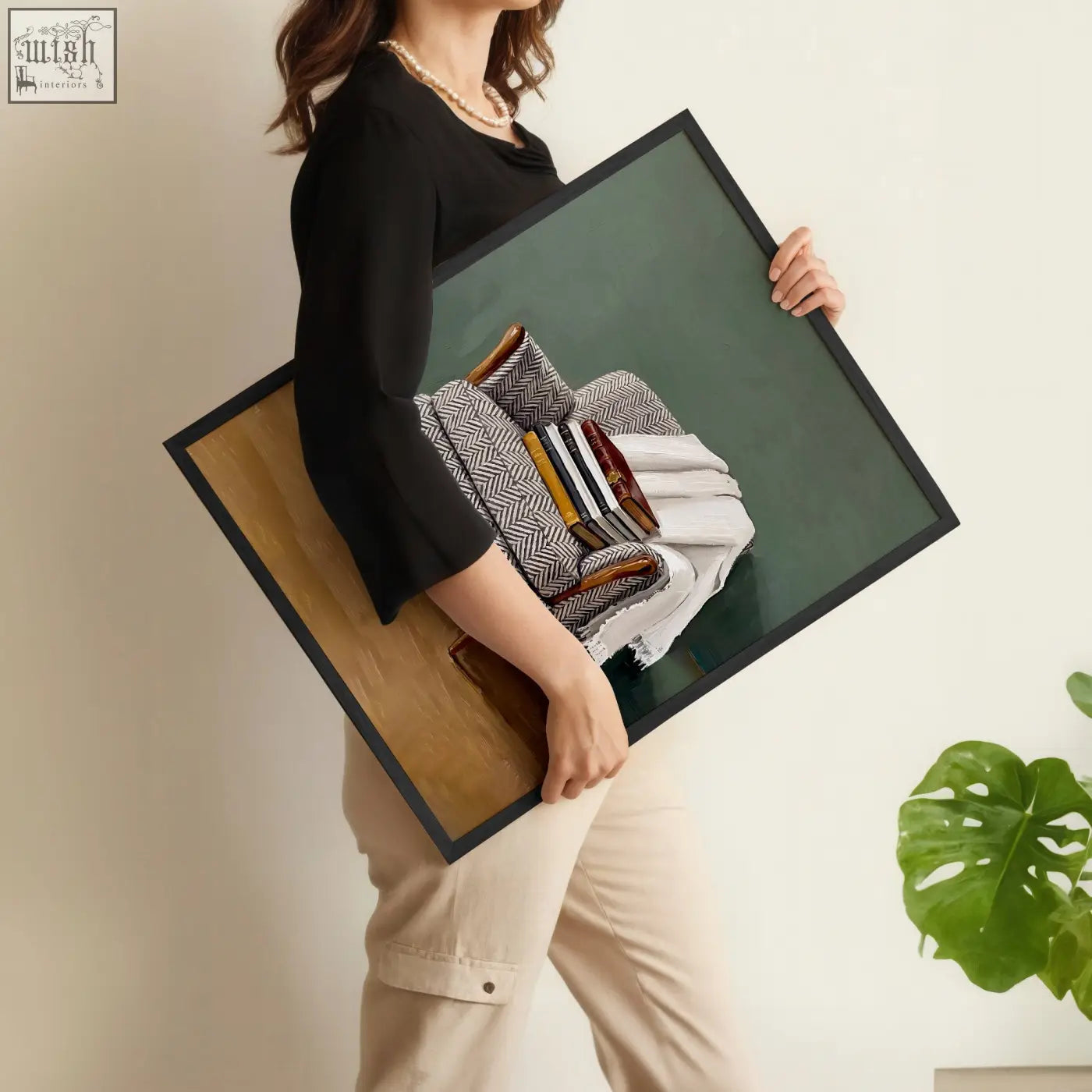 Black-framed rectangular piece wall art showing still life of folded textiles and books on deep green background