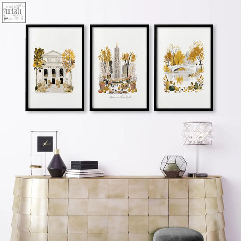 Three black framed autumn in new york city art prints hang above a gold console table in a living room wall art setup