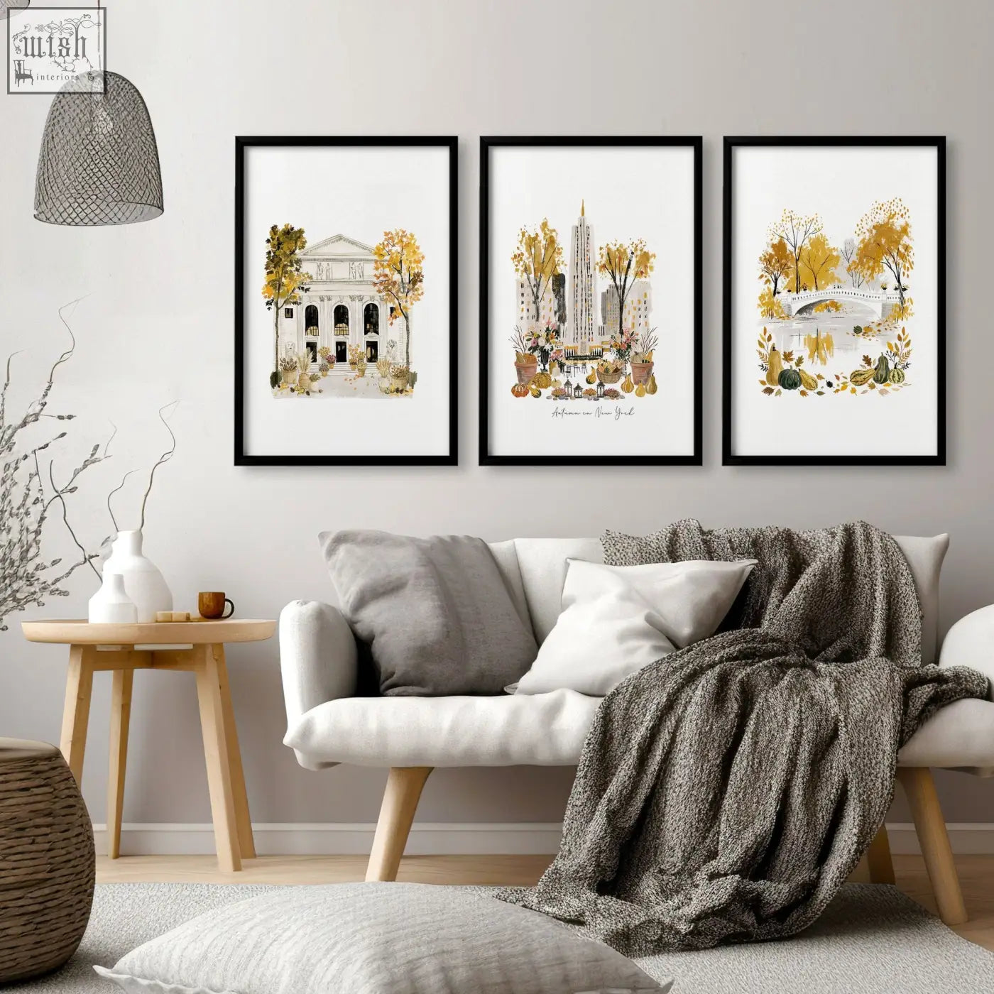 Three framed watercolor autumn art prints in black frames hanging as living room wall art above white sofa