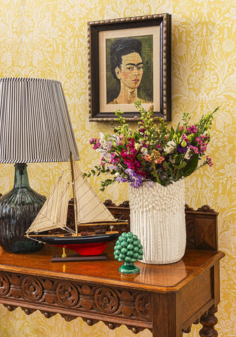 A white textured ceramic vase from cape cod sailboat collection filled with a vibrant mixed flower bouquet