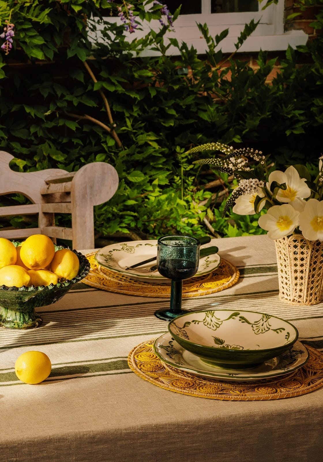 A ceramic cara shell bowl with a green rim and floral cream pattern on an ornate woven placemat