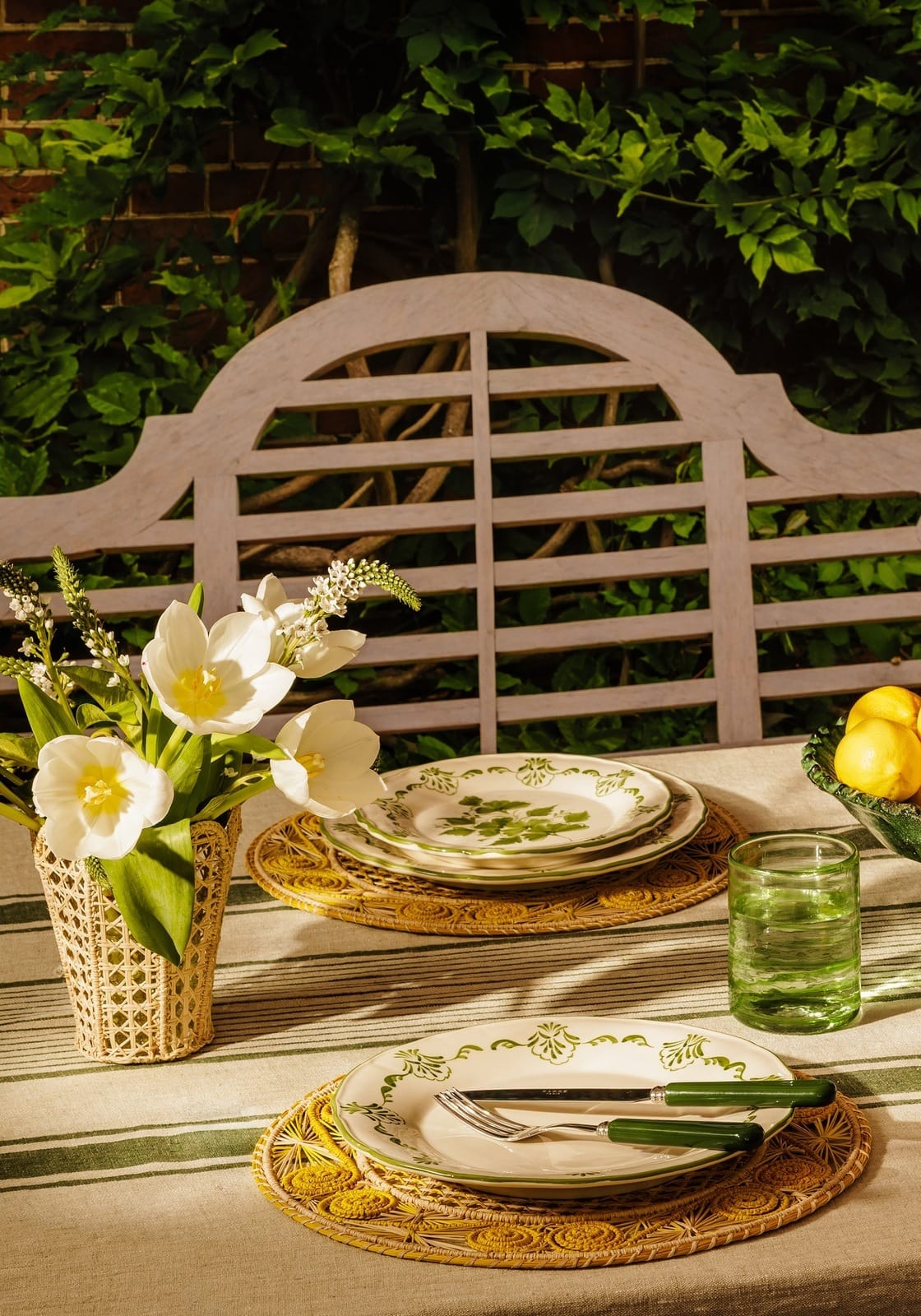 White ceramic cara shell dinner plates with green botanical patterns set on woven placemats