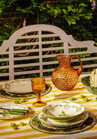 Amber glass pitcher with bubbly texture and curved handle shown next to green cara shell pasta bowl