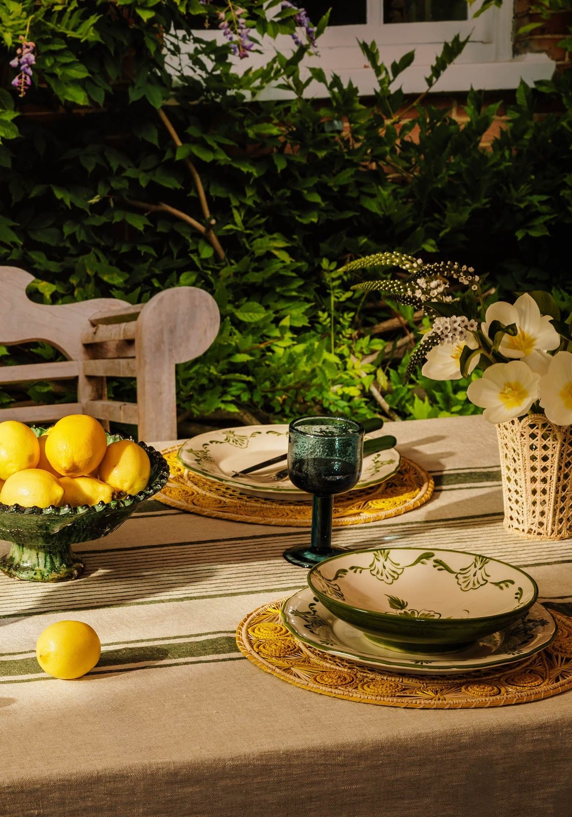 Green and cream ceramic cara shell pasta bowl with floral pattern resting on woven placemat