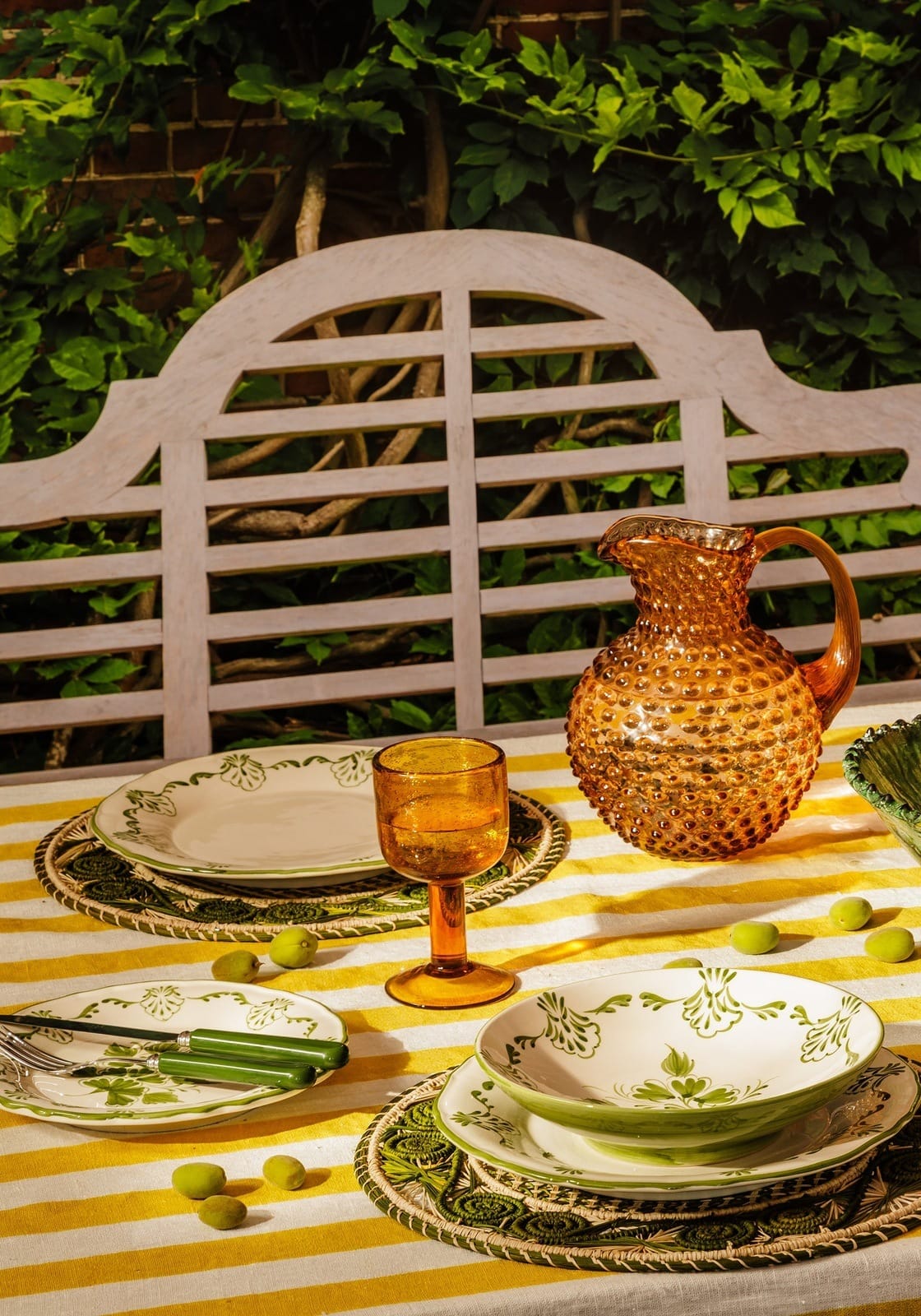Amber glass pitcher with bubbly texture and curved handle paired with green cara shell side plate for shell dinner setup