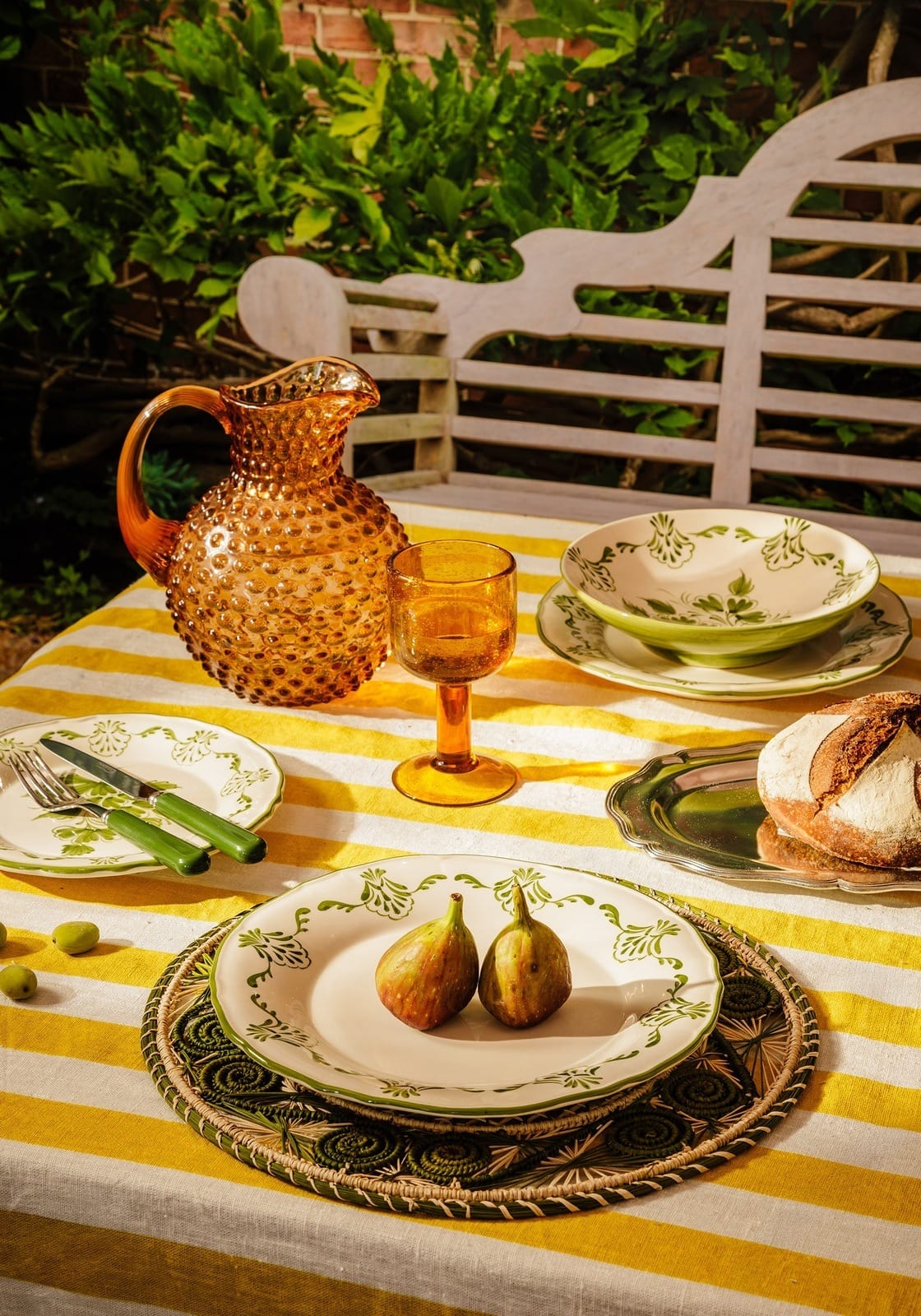 Amber glass pitcher with textured hobnail pattern and curved handle paired with cara shell dinner plate green
