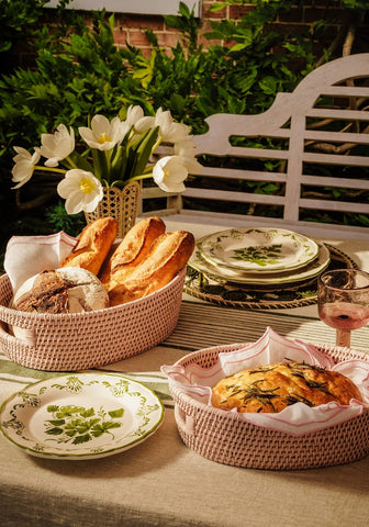 Beige woven basket holding rustic bread next to a green cara shell dinner side plate perfect for shell dinner setup