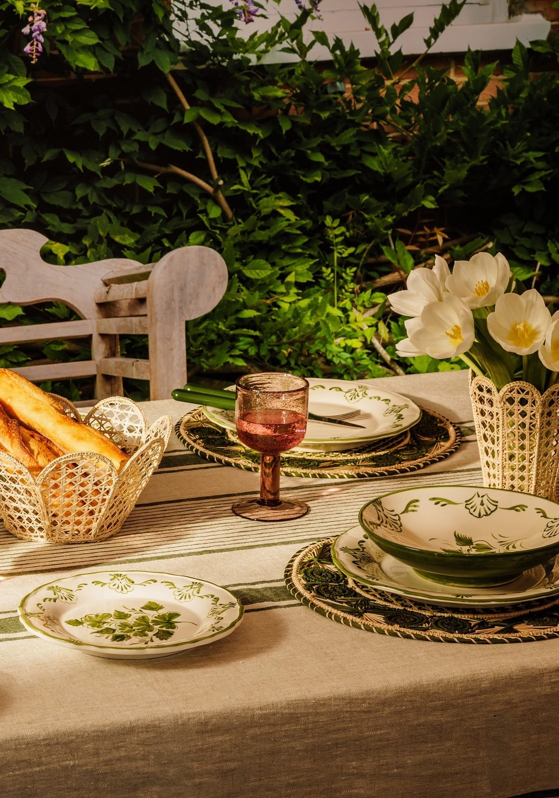 A cara shell dinner set featuring green and white ceramic shell dinner plates and matching bowl on striped cloth