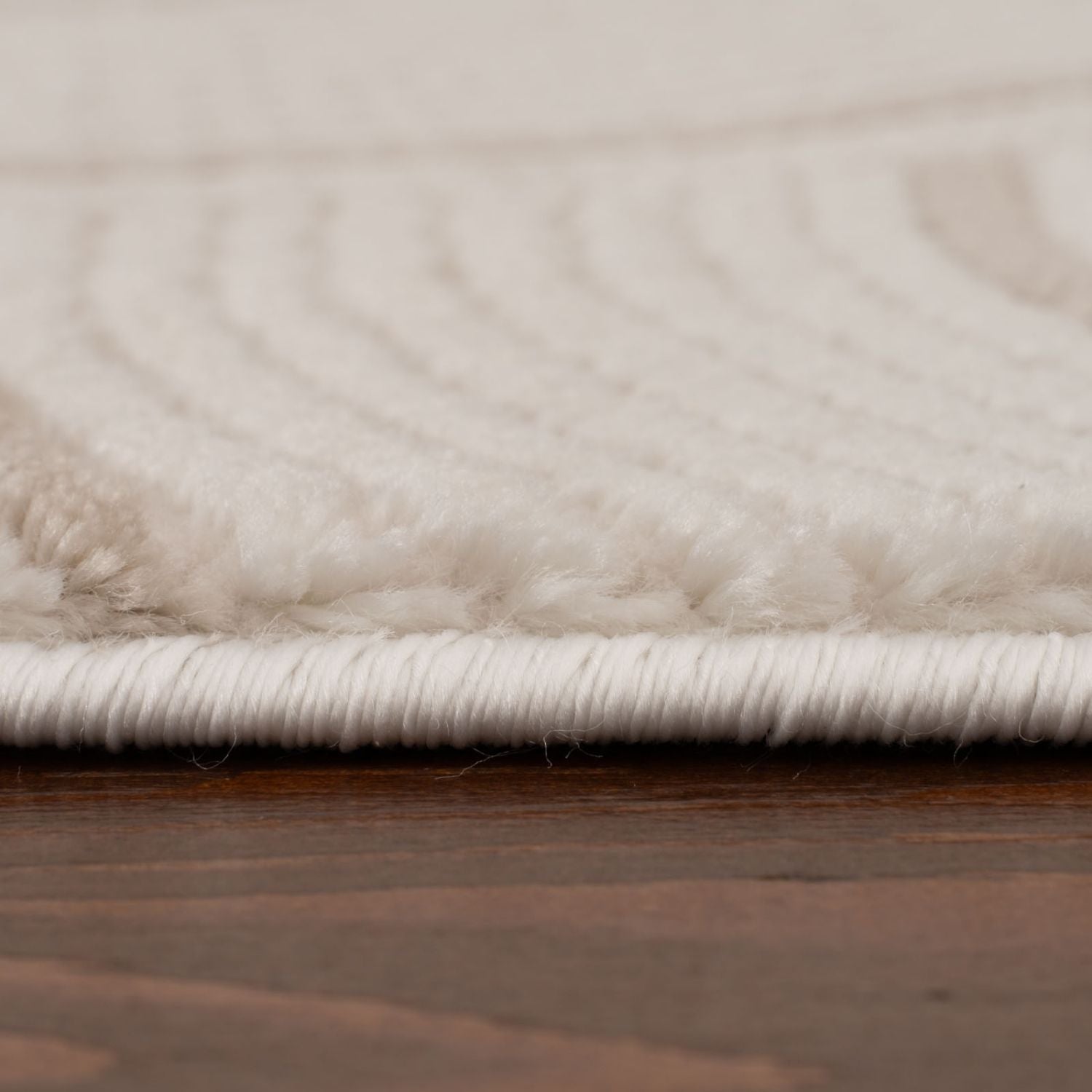 Cream-beige geometric rug with plush textured wave pattern and neatly bound white edge perfect for cozy spaces
