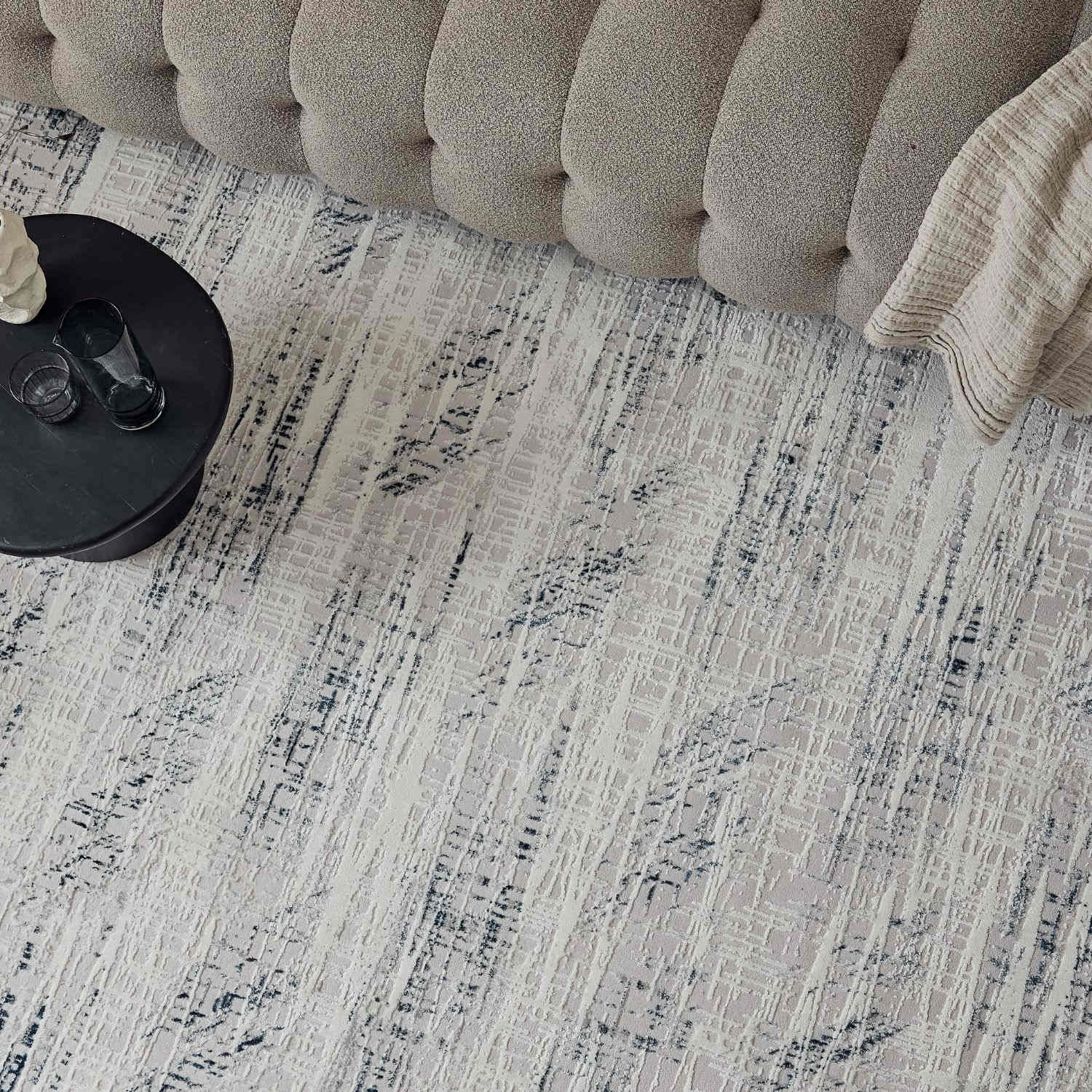 Carmel cream-blue abstract rug with textured neutral surface and black gray brushstroke designs on light beige background