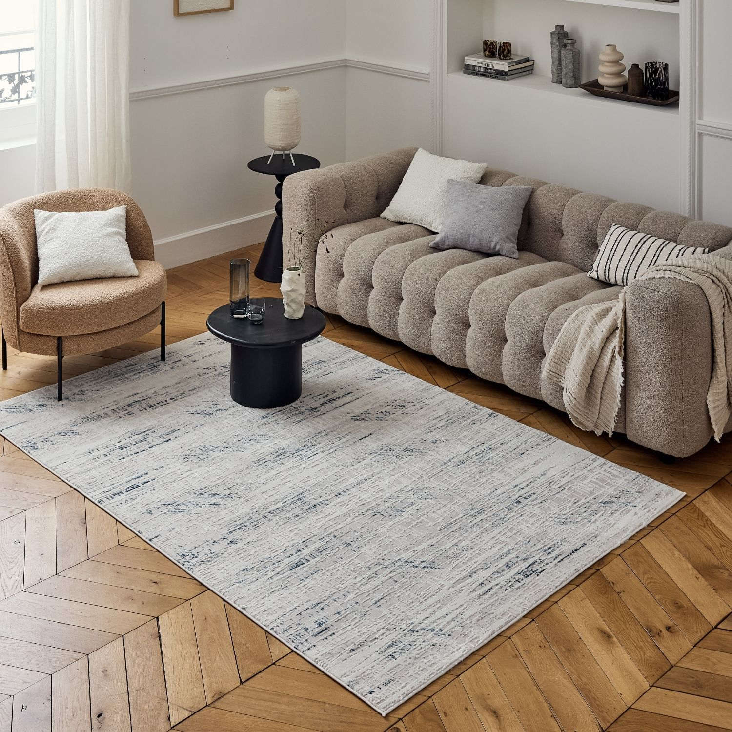 A rectangular blue abstract rug with a subtle distressed pattern in gray and cream on wooden floor