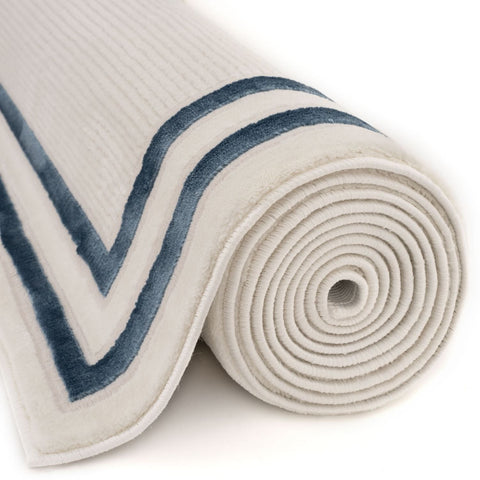 A rolled beige bordered rug with plush ribbed texture and bold navy blue v-shaped stripes along the edge