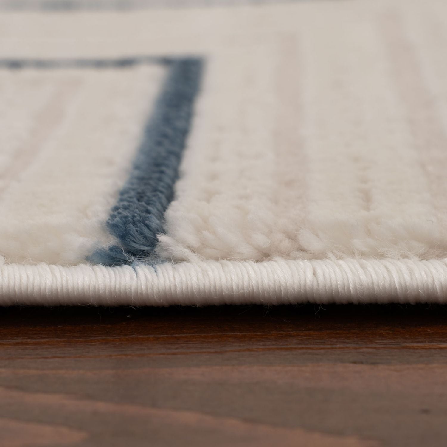 Cream-colored plush rug with a navy blue geometric border detail perfect as a stylish blue geometric rug