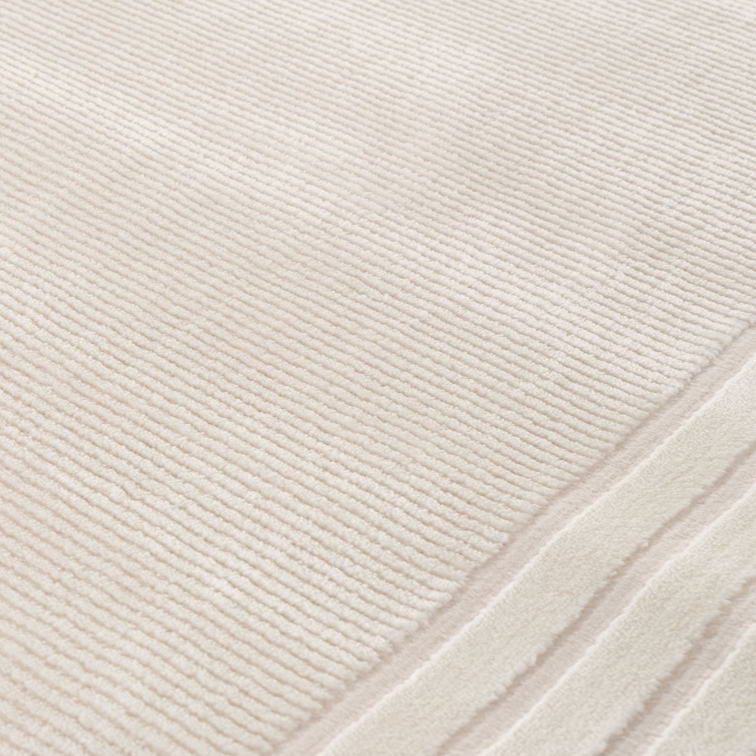Cream bordered rug with soft ribbed texture cream color and neatly stitched edges perfect for cozy spaces