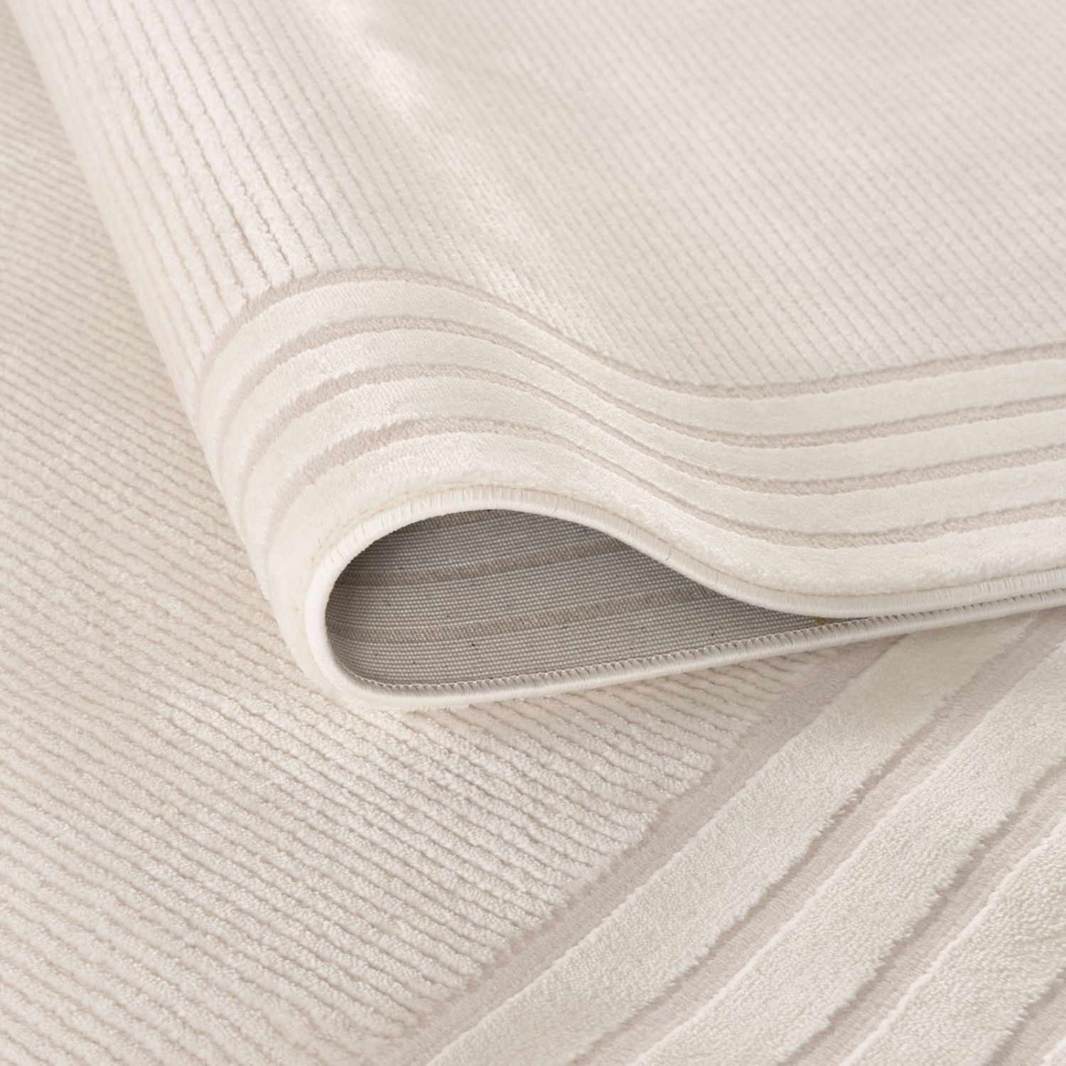 A soft carmel cream bordered rug made of off-white corduroy with plush texture and subtle ribbed pattern