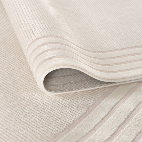 A soft carmel cream bordered rug made of off-white corduroy with plush texture and subtle ribbed pattern