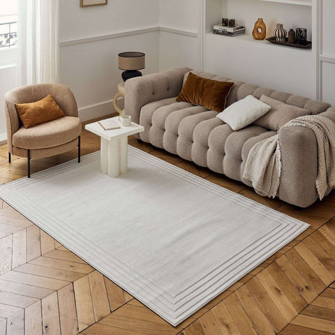 A soft off-white carmel cream bordered rug with a textured weave and subtle horizontal ribbed border