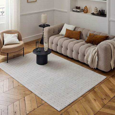 Beige tufted sofa with plush cushions and soft fabric paired with carmel cream-gold dots rug for cozy style