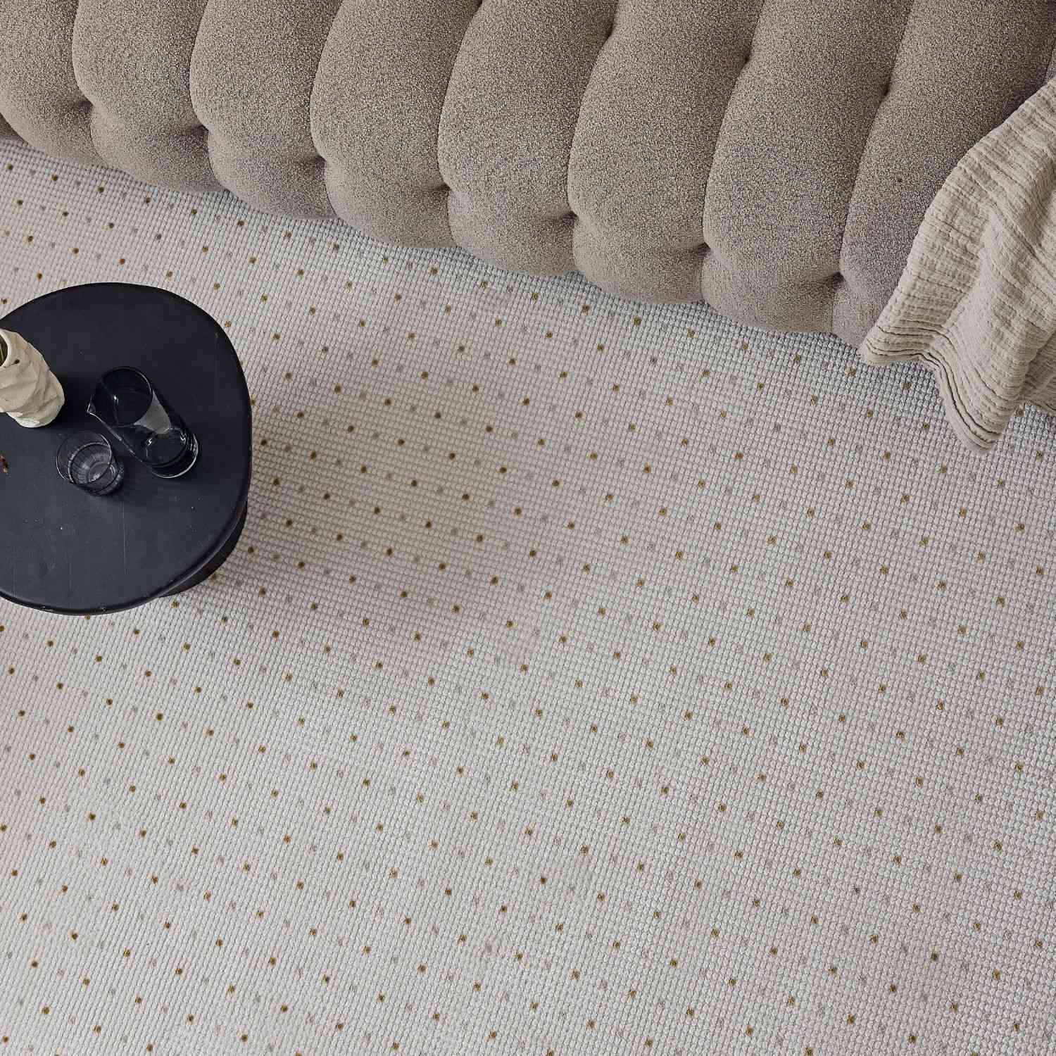 Beige tufted upholstered sofa with textured cushioned backrest paired with carmel cream gold dots rug