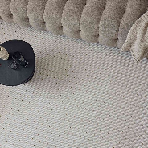 Beige tufted upholstered sofa with textured cushioned backrest paired with carmel cream gold dots rug