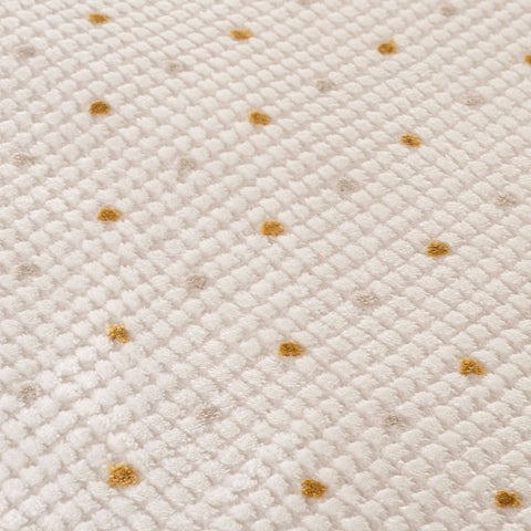 Carmel cream-gold dots rug with cream textured fabric and scattered golden-yellow polka dots for cozy decor