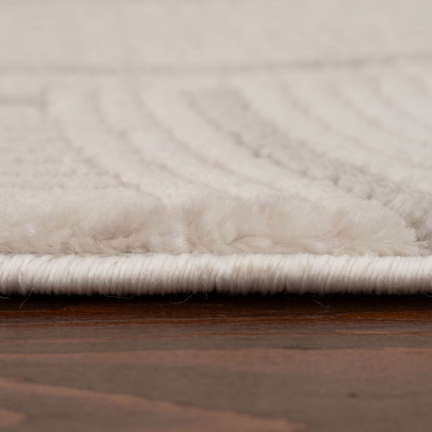 Cream-colored plush geometric rug with soft texture and neat white fringe perfect for cozy home spaces
