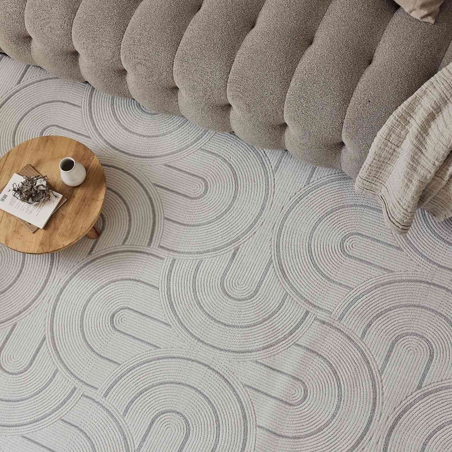 A soft light gray geometric rug with subtle concentric arc patterns perfect for cozy living spaces