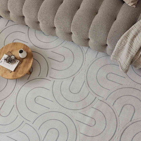 A soft light gray geometric rug with subtle concentric arc patterns perfect for cozy living spaces