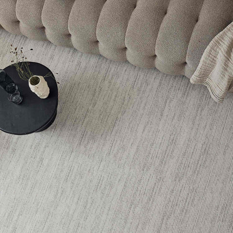 Beige tufted cushion with soft fabric and rounded segments on a carmel cream-grey striped rug