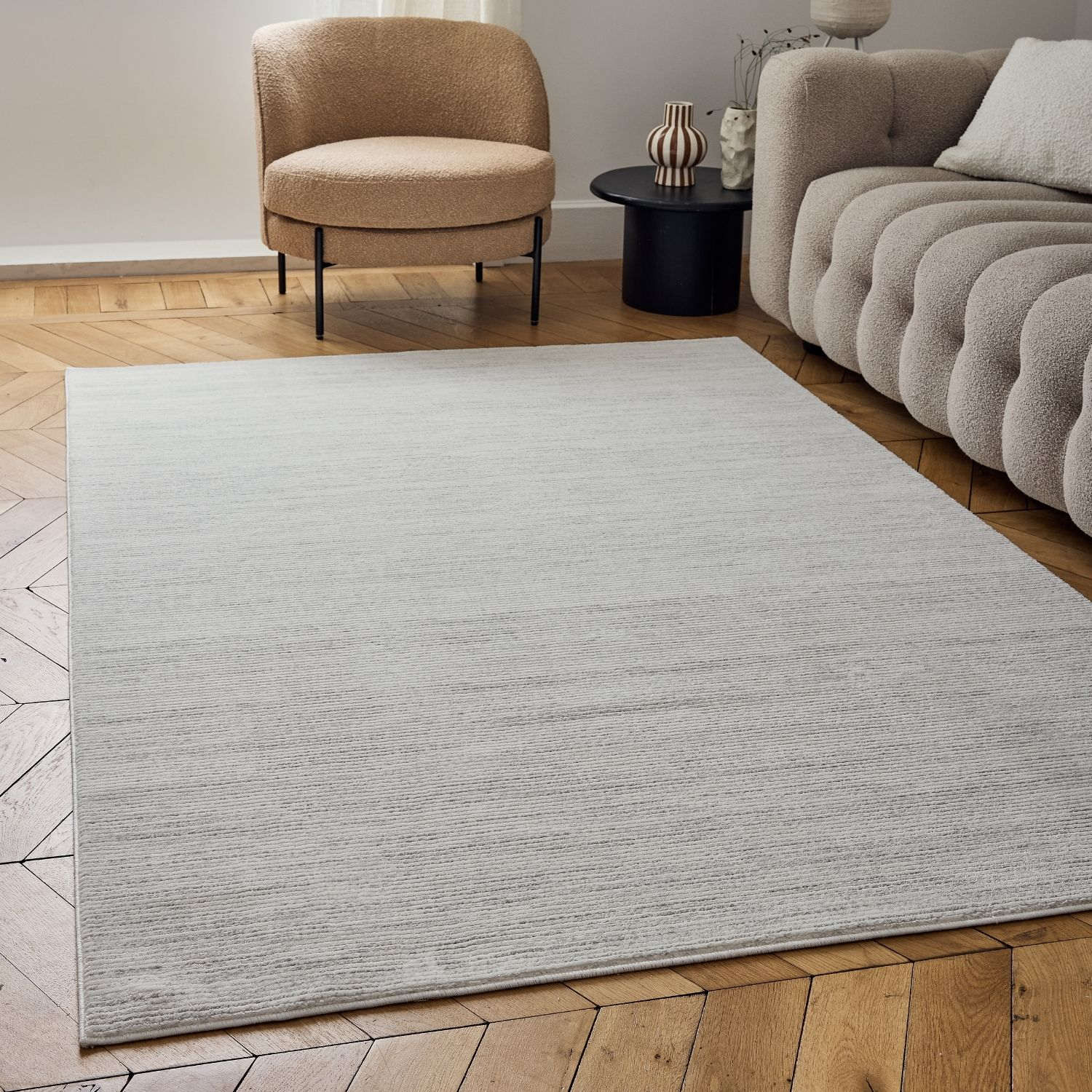 A soft light gray striped rug with subtle texture lies on a wooden floor perfect for cozy spaces