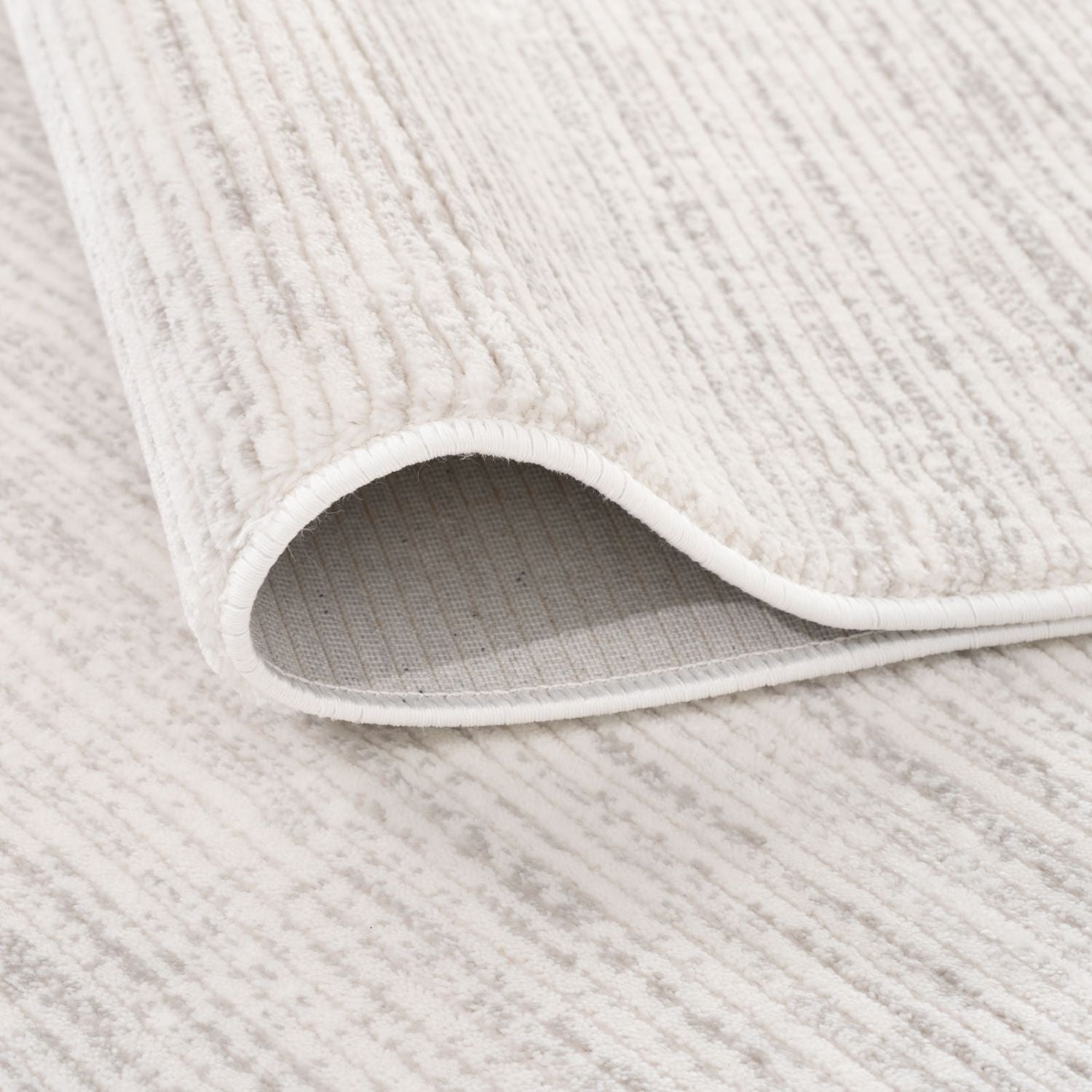 A soft off-white and gray striped rug with a ribbed textured surface perfect for cozy home spaces