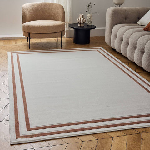 Carmel cream-terra bordered rug is a rectangular white textured rug with two brown stripes on a wooden floor