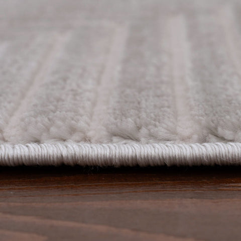 White plush geometric rug with soft textured fibers and neatly stitched border in carmel grey-cream tones