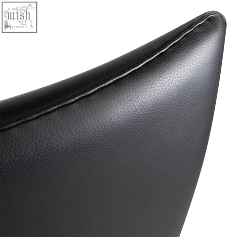 Back side of carnaby high back armchair with ottoman in black leather featuring subtle pebbled texture and stitched edge with selected high-density elastic foam