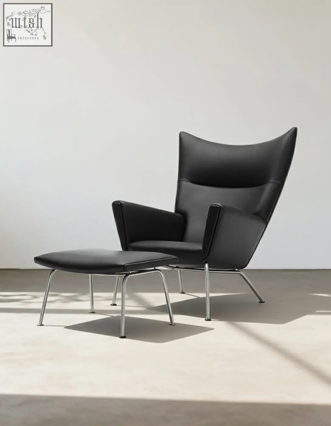 Carnaby high back armchair with ottoman in black leather featuring chrome legs and selected high-density elastic foam cushions