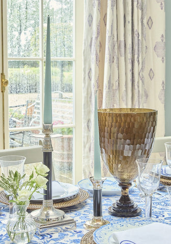 Carson’s classic pair of candle holders with slender teal candles and a gold hammered goblet with dark base nearby