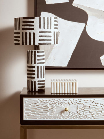 A modern white papier mache table lamp with black geometric stripes in a bold carta black and white design
