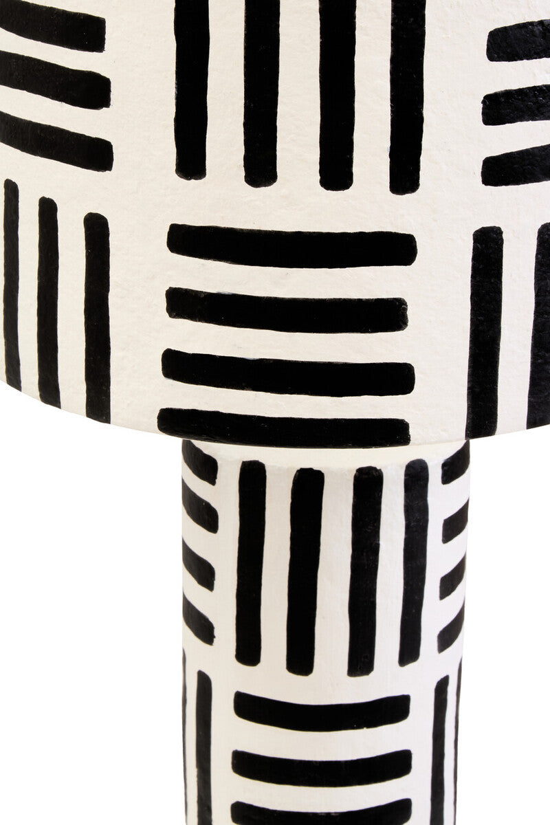 A white papier mache table lamp with bold black geometric stripes on the carton black and white papier mache model
