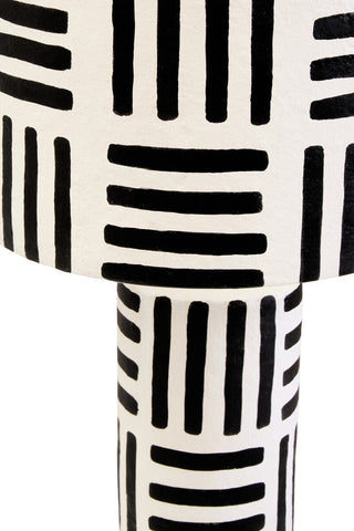 A white papier mache table lamp with bold black geometric stripes on the carton black and white papier mache model
