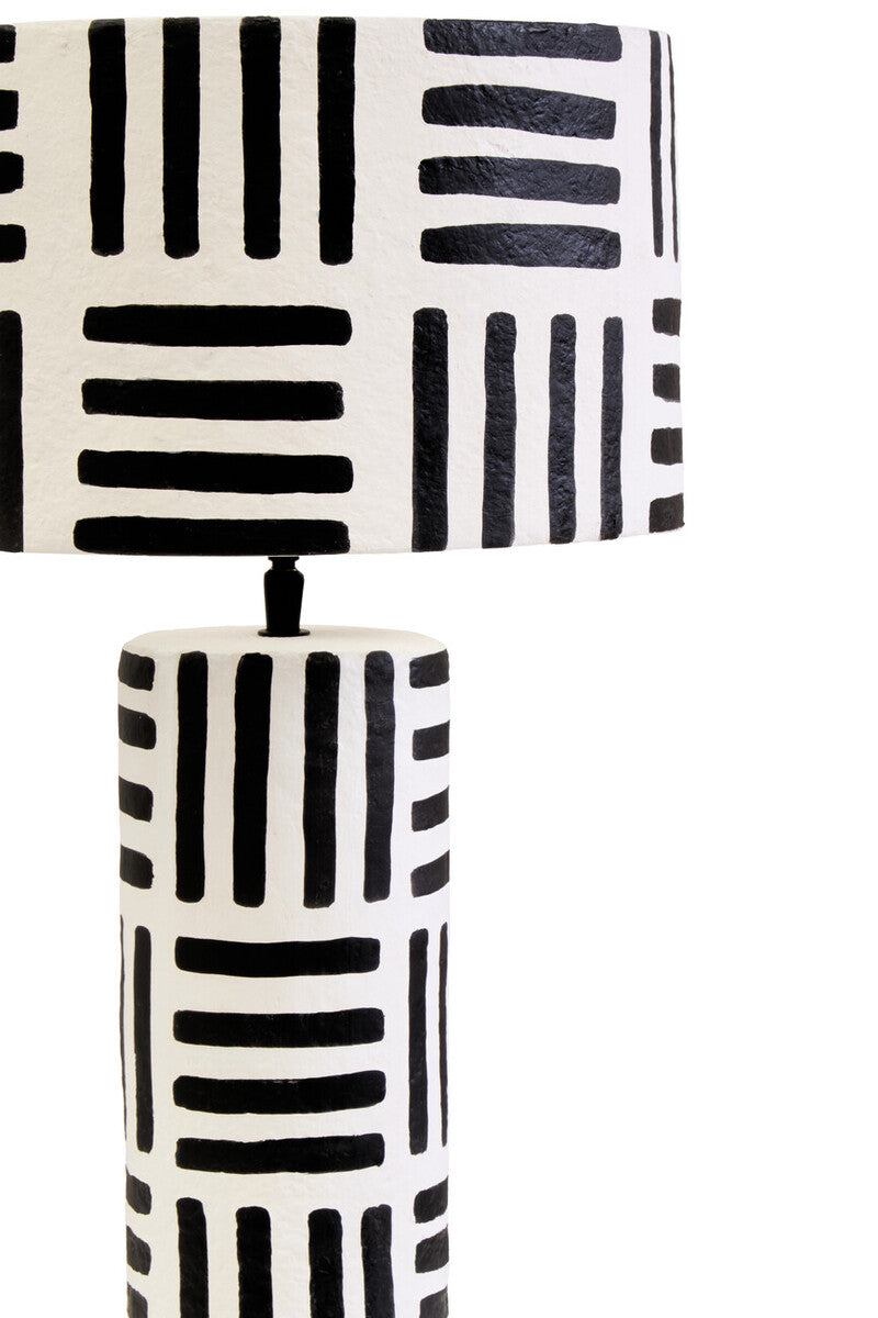 A modern mache table lamp with bold black geometric stripes on white papier mache base and shade