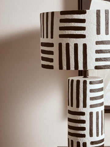 White papier mache table lamp with textured surface and bold black geometric lines for stylish lighting