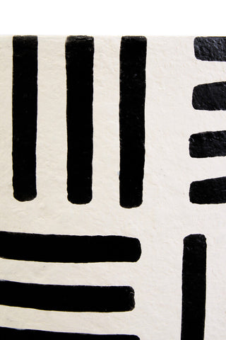 Black brushstroke lines on textured off white white papier mache surface of carta mache table lamp
