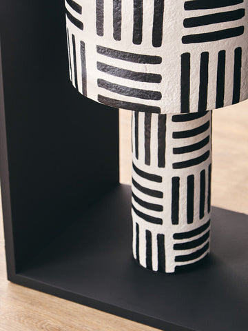 A modern black and white papier mache table lamp with geometric lines and a textured surface perfect for any room