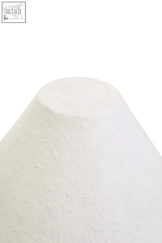 A white papier mache table lamp with a textured matte finish shaped like a cone for ambient lighting