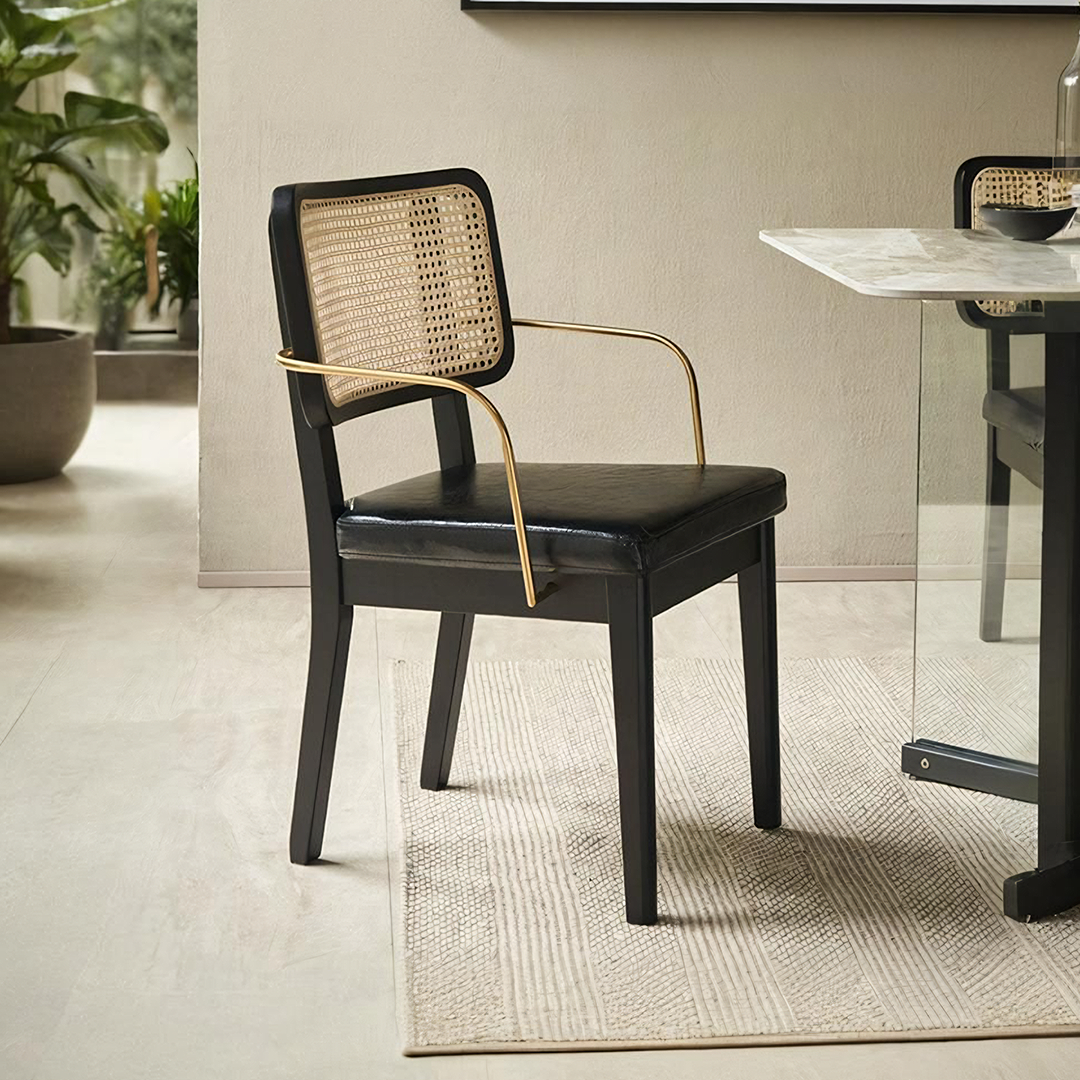 Cassie black dining chair with black cane-back, gold-tone metal arms, and leather seat for stylish dining seating